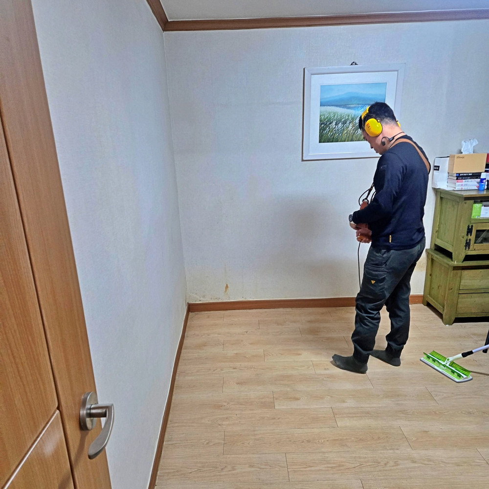 작은방 바닥에서 청음 장비를 사용해 점검하는 작업자
